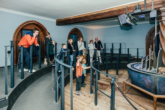 Besucher mit Audioguides betrachten eine historische mechanische Ausstellung im Museum